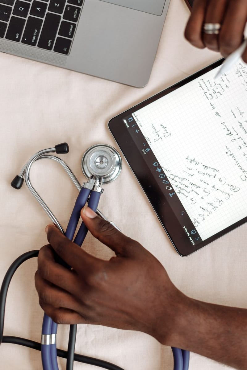 A physician's stethoscope beside a tablet of handwritten exam notes