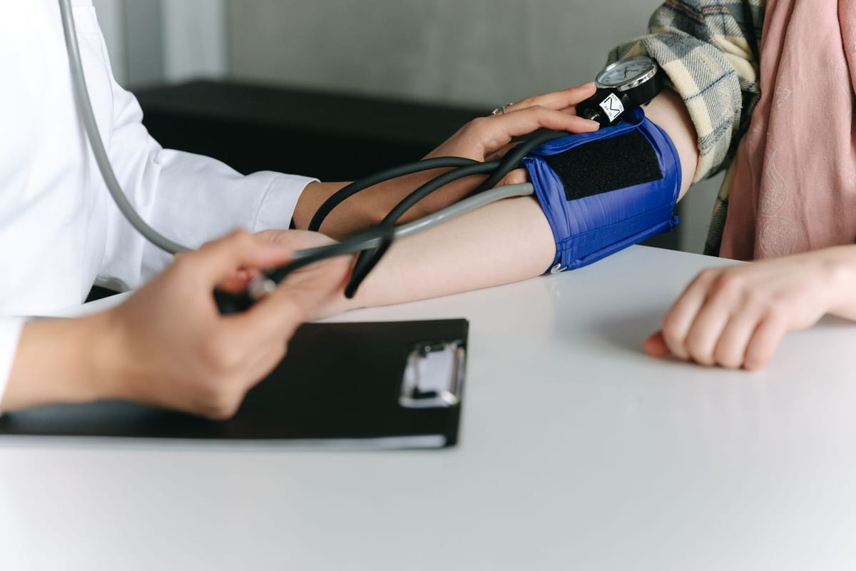 A clinician taking a patient's blood pressure with a cuff and stethoscope
