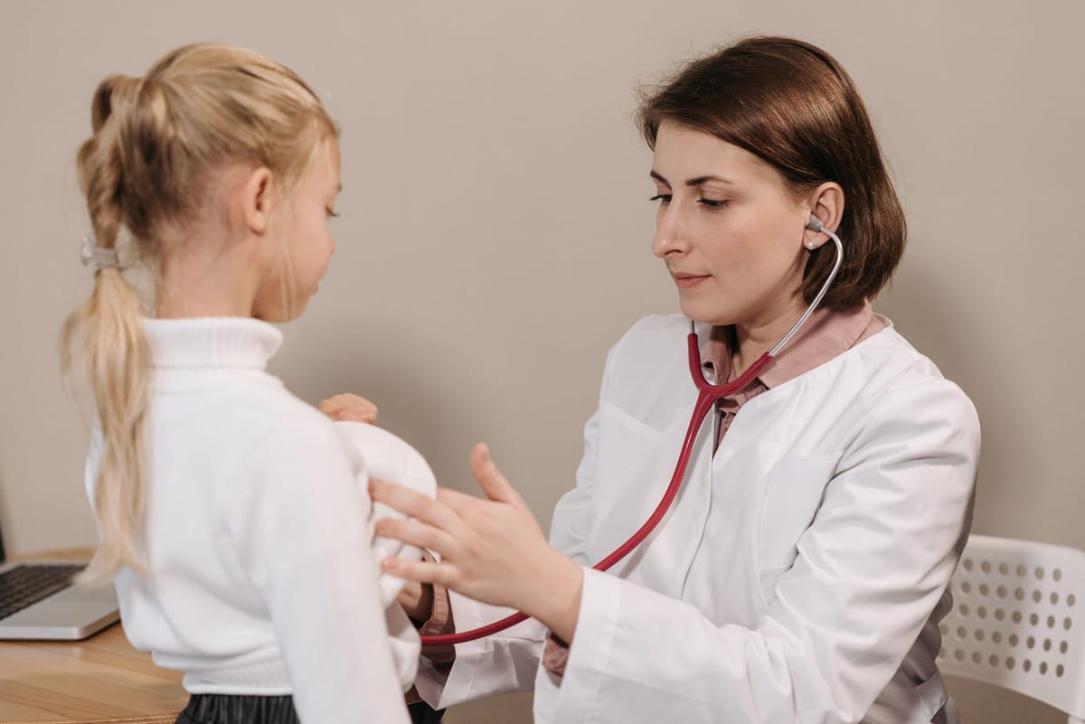 A doctor listening to a young girl's breathing with a stethoscope