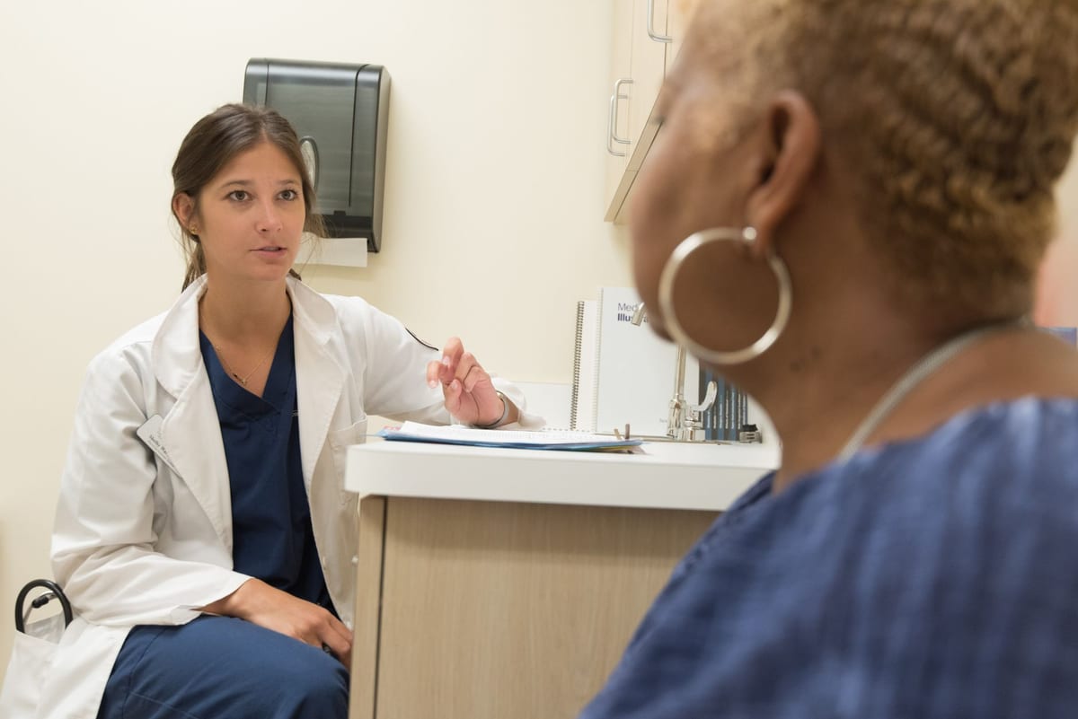 A physician talking with a woman patient in an exam room